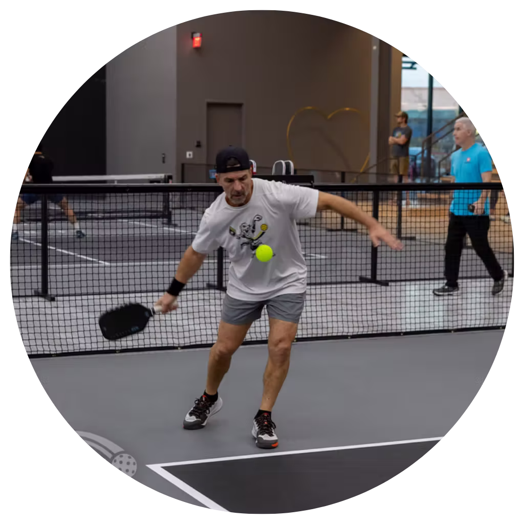Austin area pickleball player hitting a third shot drop on indoor court at Apex Pickleball Clubs in Cedar Park Texas