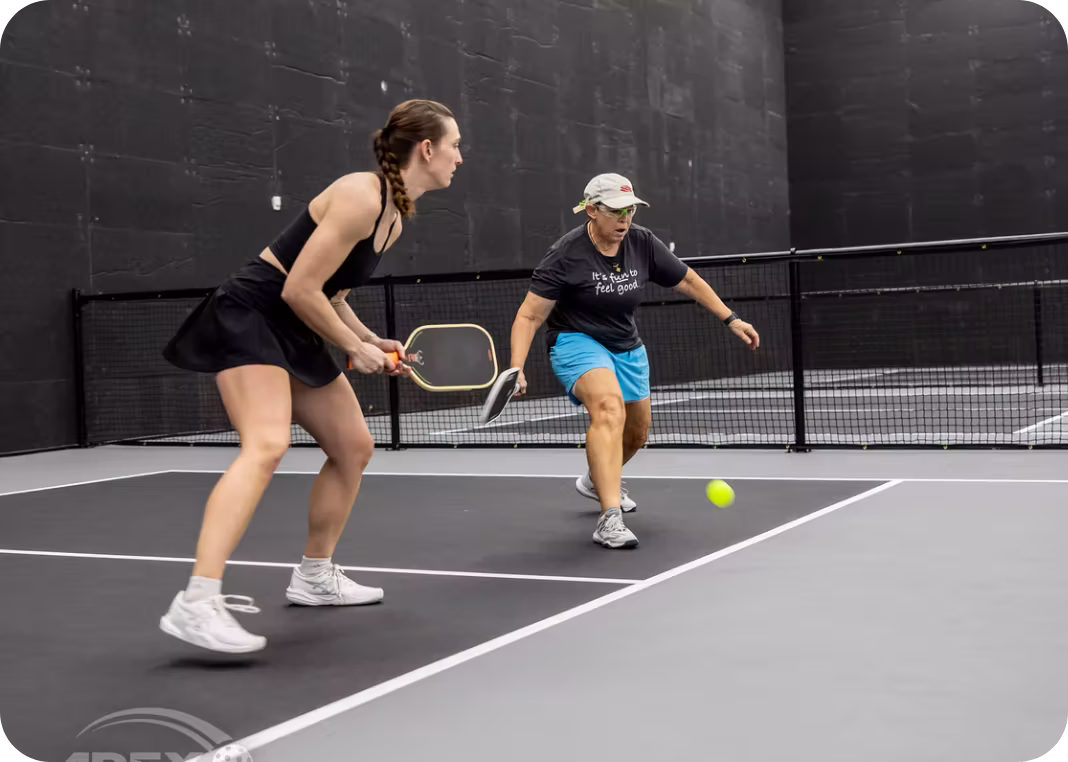 Women playing competitive doubles pickleball on indoor court at Apex Pickleball Clubs in Cedar Park Texas