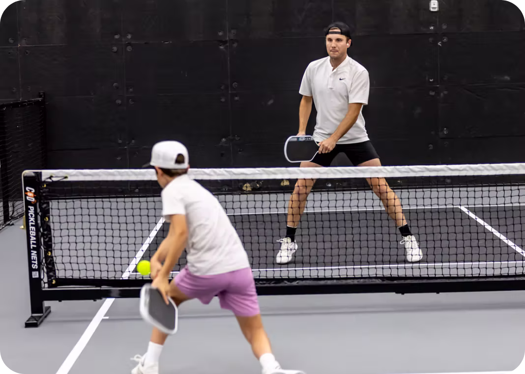 Two pickleball players positioned at the net during doubles play on indoor court at Apex Pickleball Clubs Cedar Park Texas